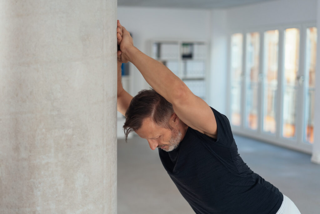 man-stretching-against-wall